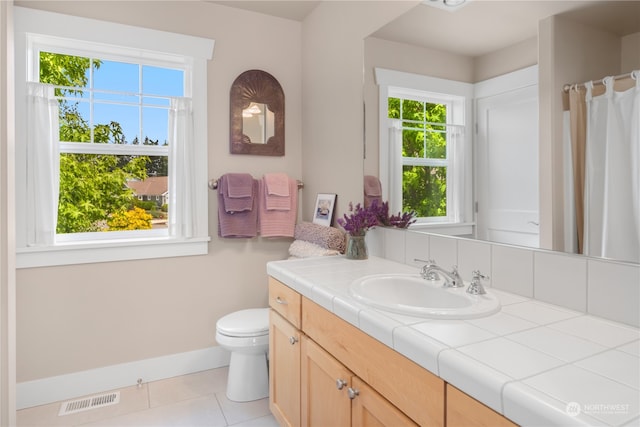 bathroom featuring tile patterned floors, vanity, a wealth of natural light, and toilet