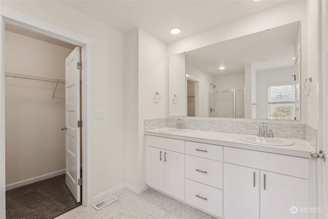 bathroom featuring vanity, decorative backsplash, and walk in shower