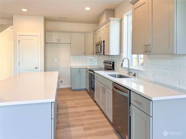 kitchen featuring sink, a center island, light hardwood / wood-style flooring, stainless steel appliances, and backsplash