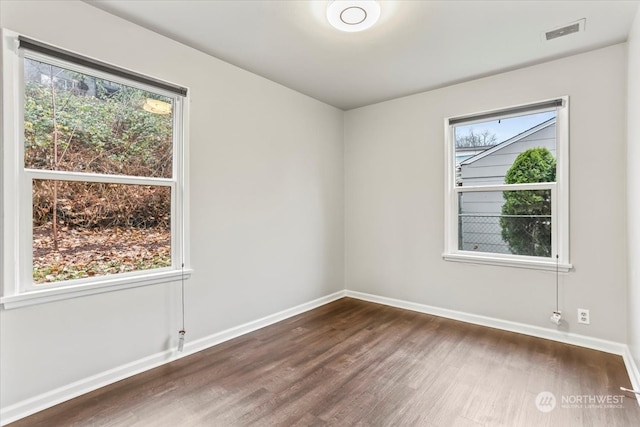 unfurnished room featuring dark wood-type flooring and a healthy amount of sunlight