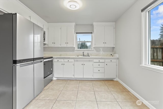 kitchen with white cabinets, light tile patterned flooring, tasteful backsplash, and stainless steel appliances