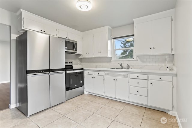 kitchen with stainless steel appliances, light tile patterned floors, backsplash, sink, and white cabinetry