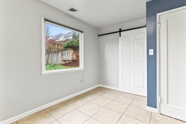 unfurnished bedroom with light tile patterned floors, a barn door, and multiple windows