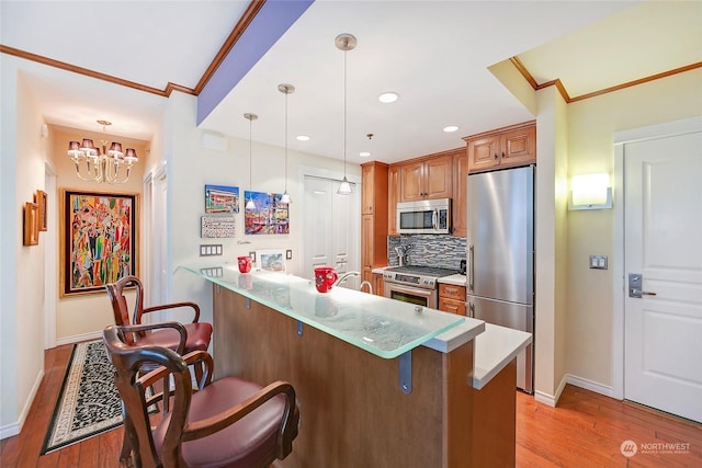 kitchen featuring stainless steel appliances, ornamental molding, a kitchen bar, decorative light fixtures, and kitchen peninsula