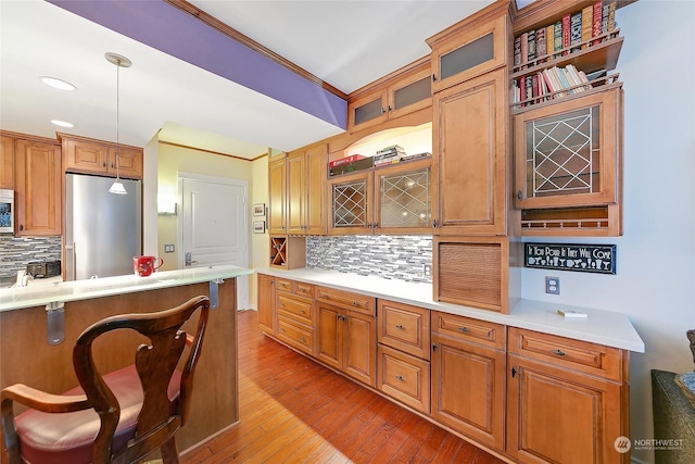 kitchen featuring pendant lighting, crown molding, a breakfast bar area, stainless steel appliances, and light wood-type flooring