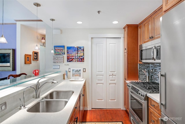 kitchen featuring sink, decorative light fixtures, stainless steel appliances, light hardwood / wood-style floors, and decorative backsplash