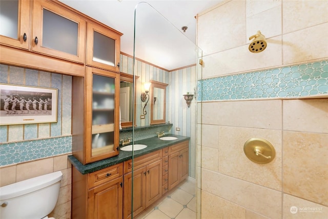 bathroom with tile patterned floors, toilet, crown molding, tile walls, and vanity