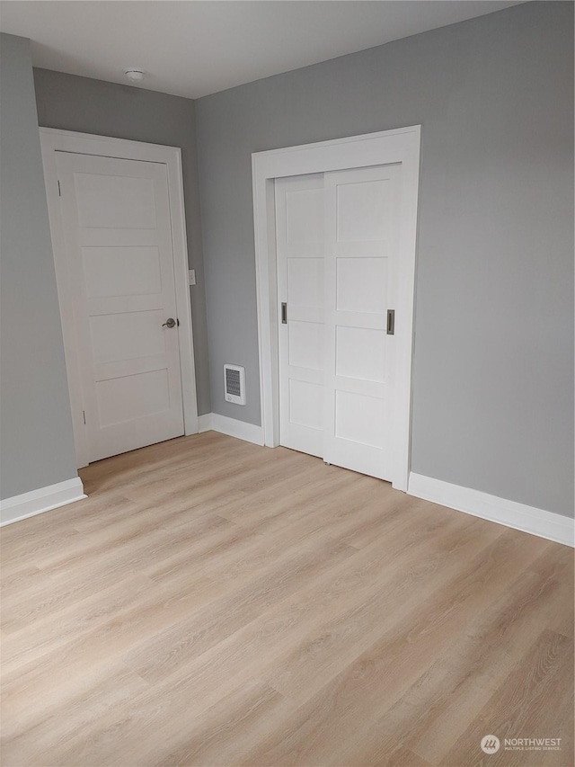 unfurnished bedroom with light wood finished floors, a closet, and baseboards