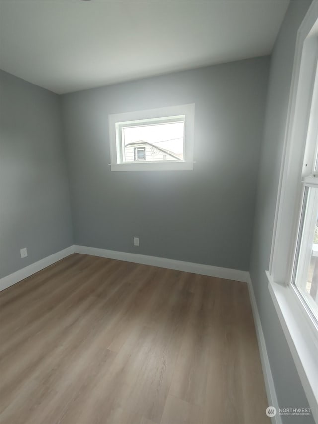 spare room featuring light wood-type flooring and baseboards