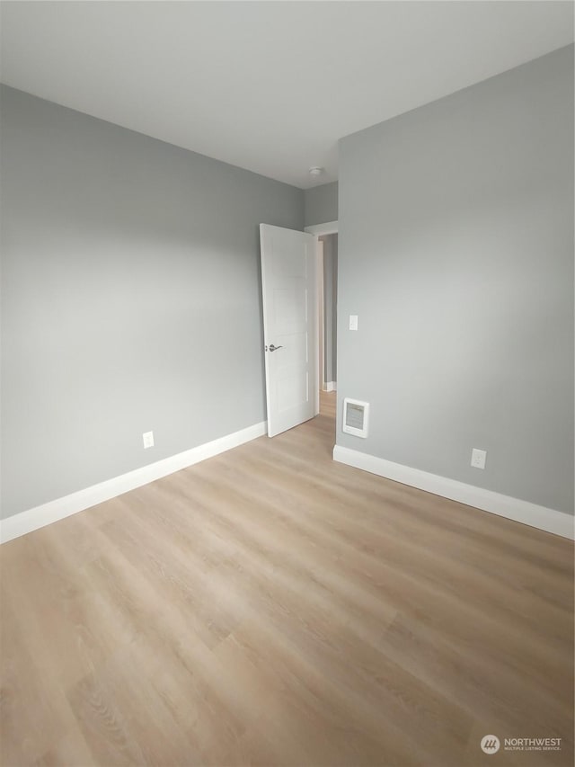 empty room with light wood-type flooring, baseboards, and visible vents