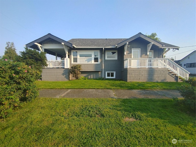 view of front of home featuring a porch, stairway, a front yard, and a shingled roof