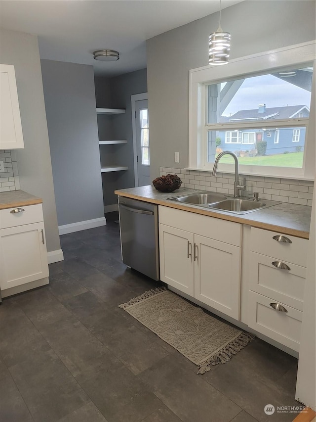 kitchen featuring dishwasher, tasteful backsplash, a sink, and white cabinetry