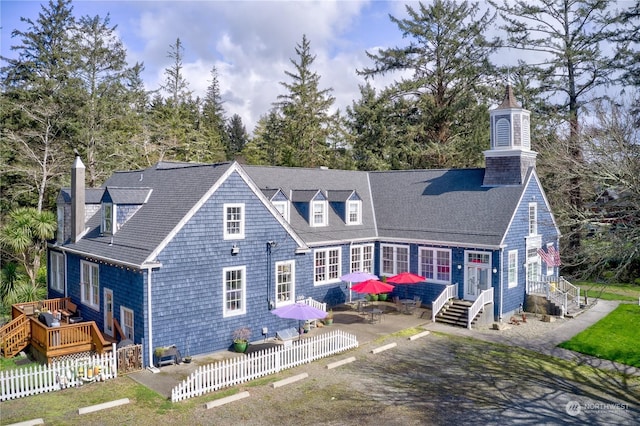 rear view of property with a shingled roof, a chimney, a patio area, and fence