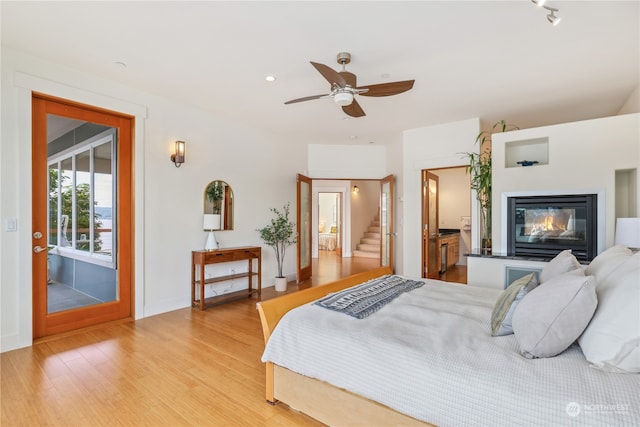 bedroom with connected bathroom, access to exterior, ceiling fan, and light wood-type flooring