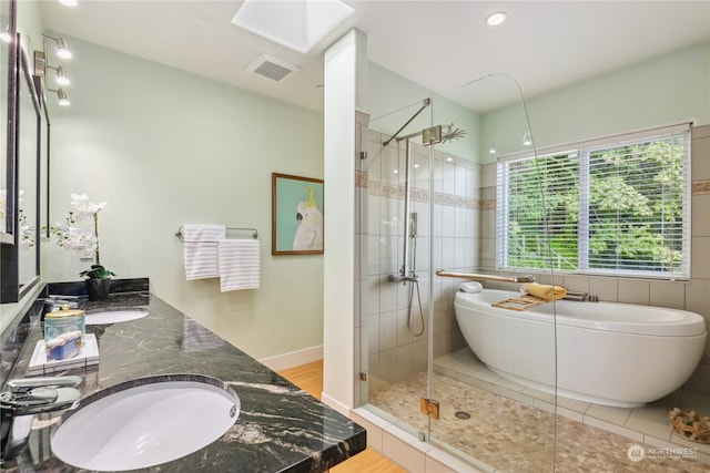 bathroom featuring hardwood / wood-style floors, vanity, a skylight, and independent shower and bath