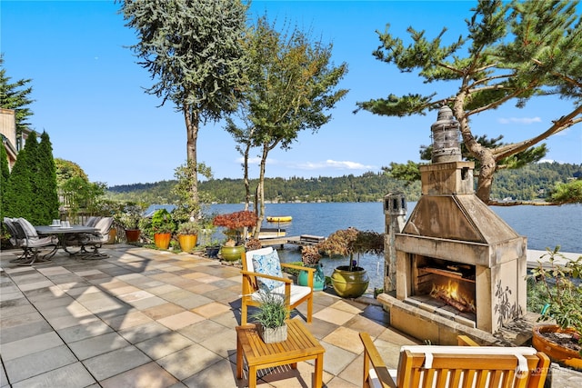 view of patio / terrace featuring an outdoor stone fireplace and a water view