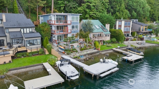 exterior space with a balcony, a lawn, and a water view