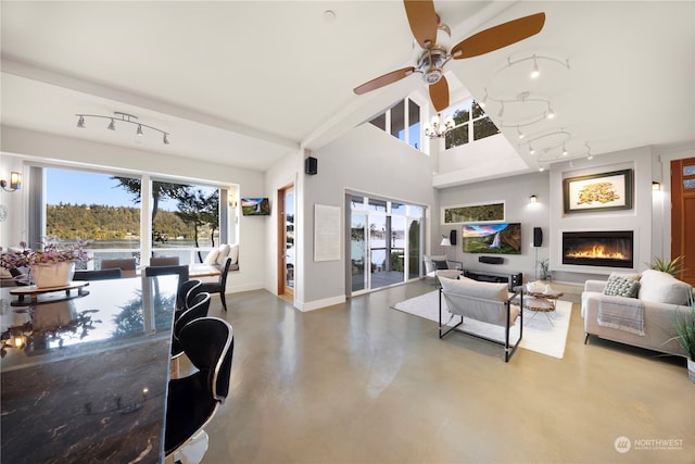 living room featuring ceiling fan, rail lighting, concrete flooring, and lofted ceiling