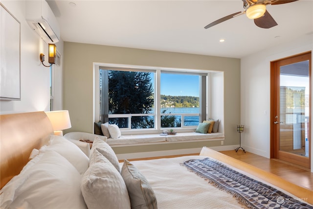 bedroom with a wall mounted AC, wood-type flooring, access to exterior, and ceiling fan