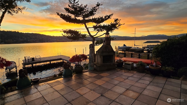 patio terrace at dusk with a boat dock and a water view