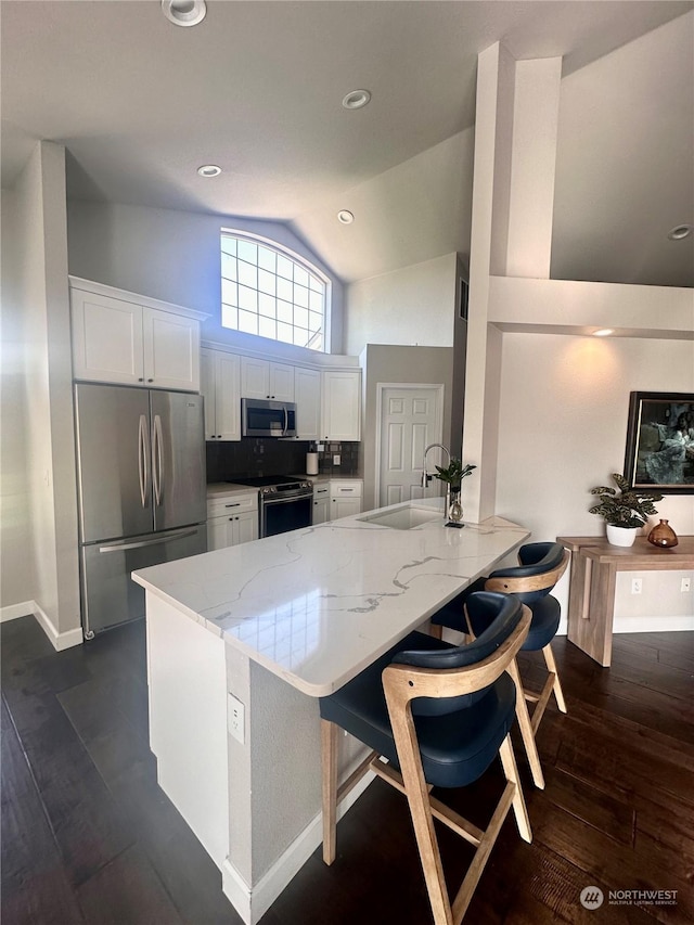 kitchen with stainless steel appliances, a breakfast bar, white cabinets, and kitchen peninsula