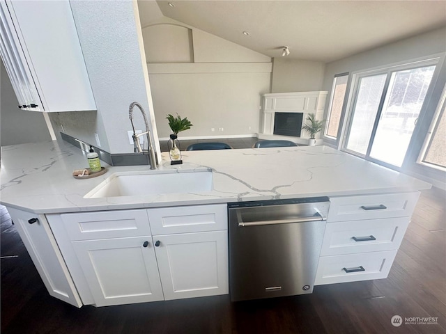 kitchen with vaulted ceiling, white cabinetry, dishwasher, sink, and light stone countertops