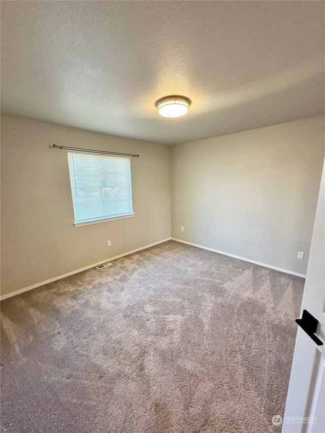 carpeted spare room with a textured ceiling