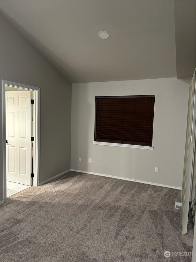 spare room with vaulted ceiling and dark carpet