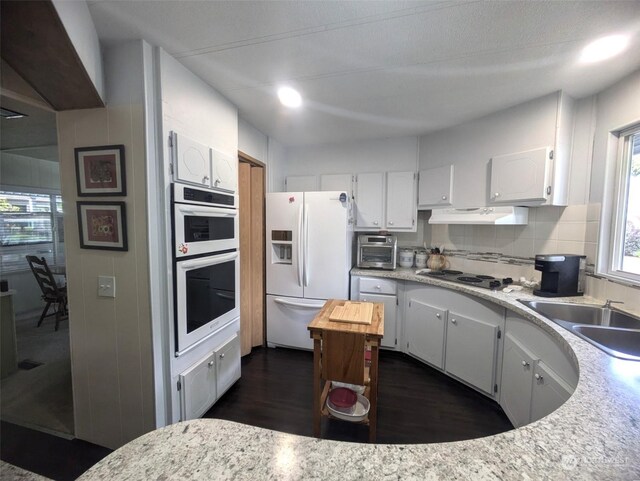 kitchen featuring white cabinetry, white appliances, dark hardwood / wood-style flooring, and sink