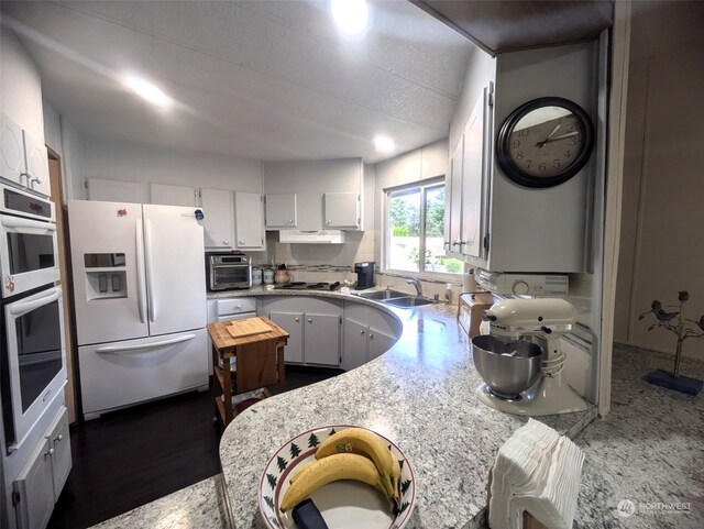 kitchen featuring white refrigerator with ice dispenser, gas stovetop, white cabinets, sink, and double oven