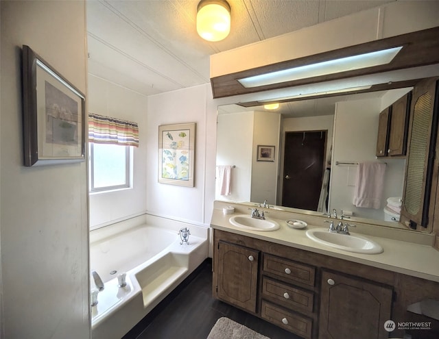 bathroom with a washtub, a textured ceiling, and vanity