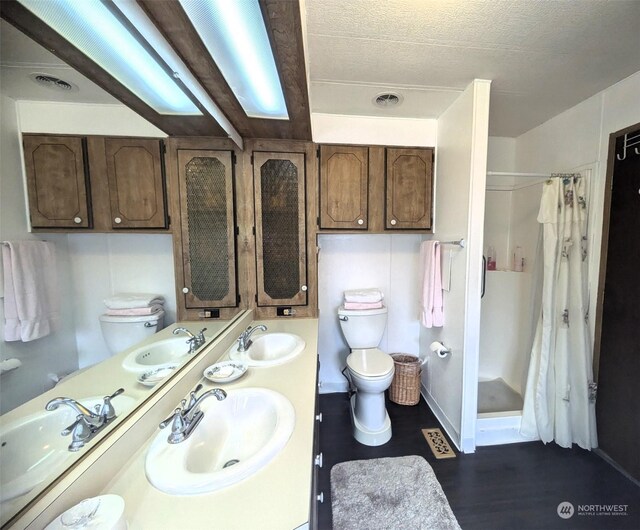 bathroom with hardwood / wood-style floors, walk in shower, toilet, and vanity