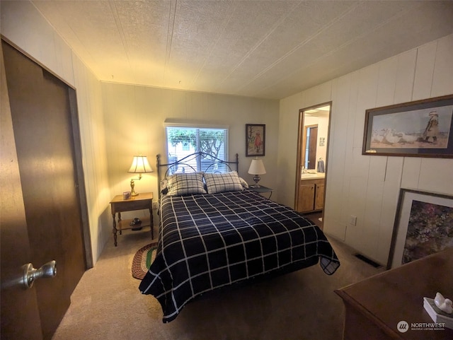 carpeted bedroom with a textured ceiling and connected bathroom