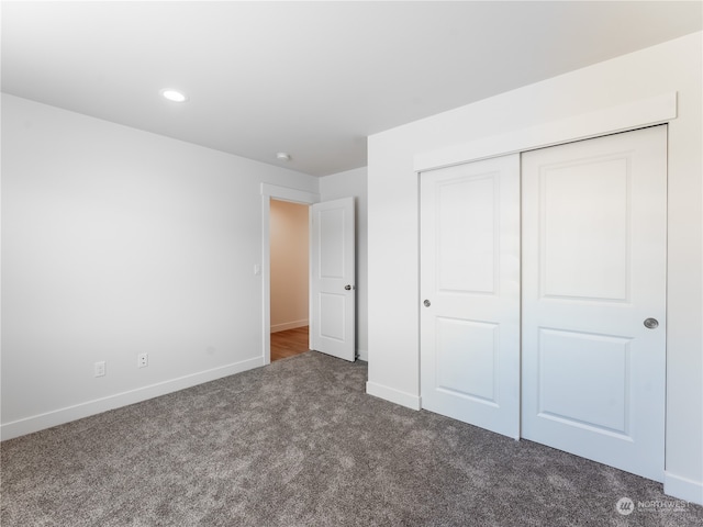 unfurnished bedroom with a closet and dark colored carpet