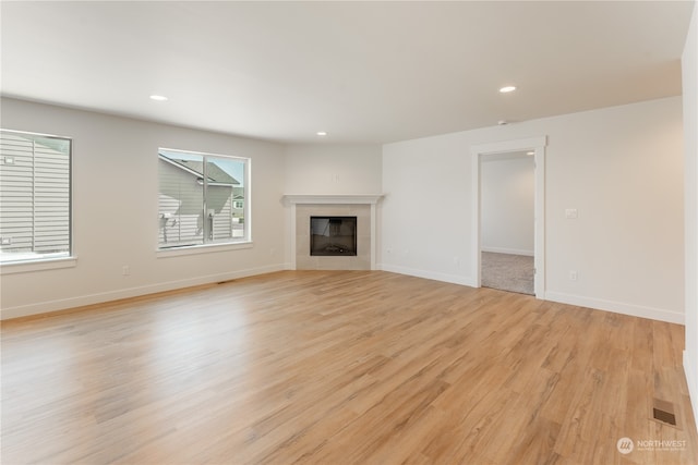 unfurnished living room with light hardwood / wood-style flooring and a tile fireplace