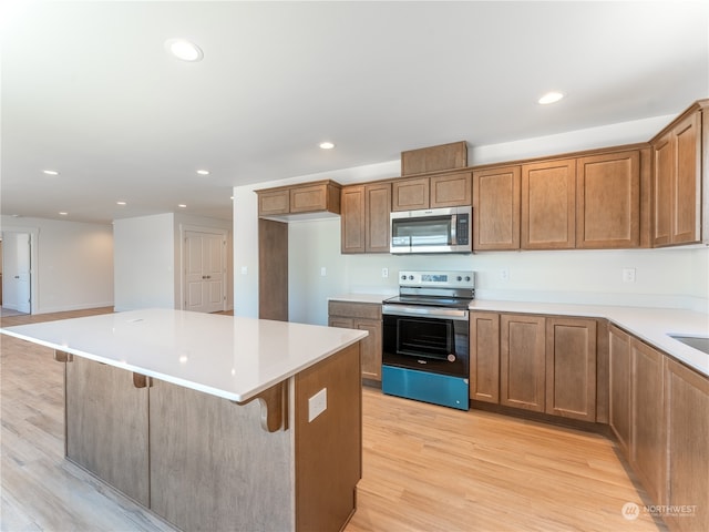 kitchen with a center island, range with electric stovetop, a breakfast bar, and light wood-type flooring