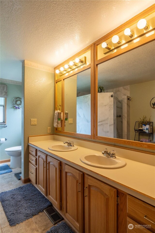 bathroom with a textured ceiling, a sink, and visible vents