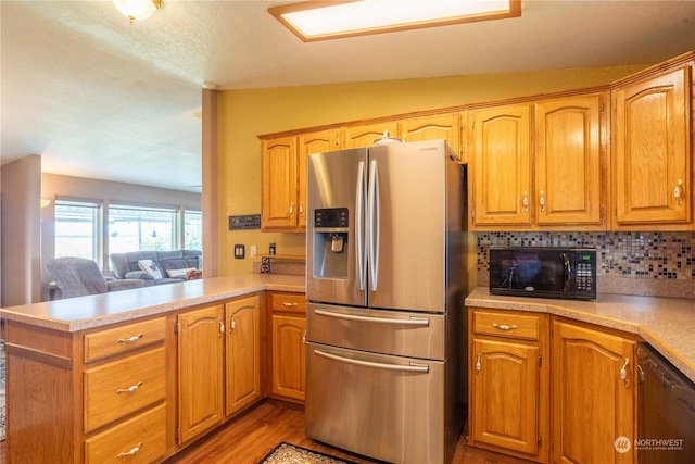 kitchen featuring lofted ceiling, black appliances, a peninsula, and light countertops