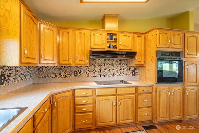 kitchen featuring vaulted ceiling, black appliances, light countertops, and under cabinet range hood