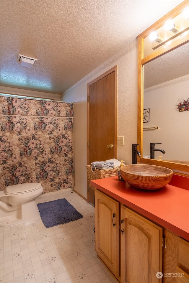 full bathroom featuring visible vents, toilet, a textured ceiling, vanity, and tile patterned floors