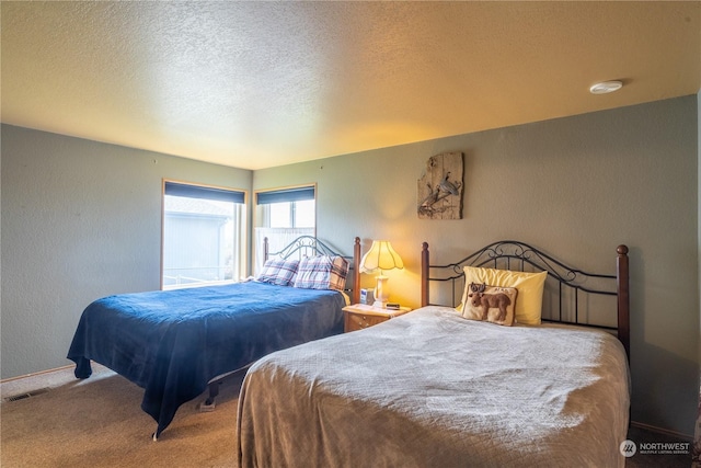 bedroom with carpet, visible vents, a textured ceiling, and a textured wall