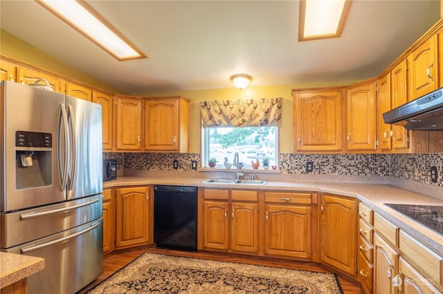 kitchen with under cabinet range hood, a sink, light countertops, backsplash, and black appliances