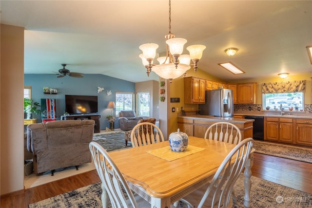 dining room with vaulted ceiling, ceiling fan with notable chandelier, and wood finished floors