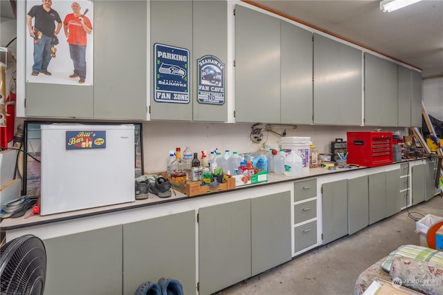 kitchen featuring gray cabinets, unfinished concrete flooring, and light countertops