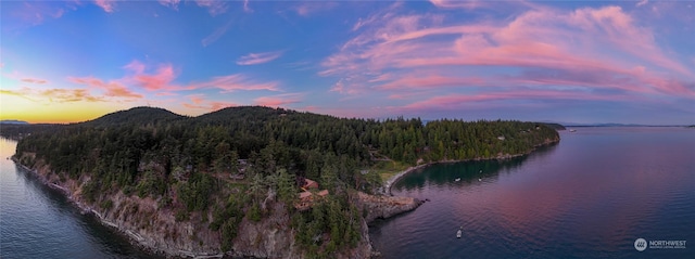 aerial view at dusk featuring a water and mountain view