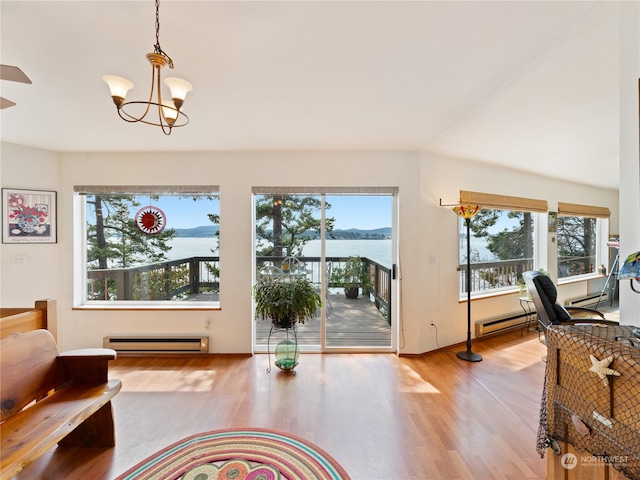 living room with baseboard heating, light wood-type flooring, a water view, and plenty of natural light