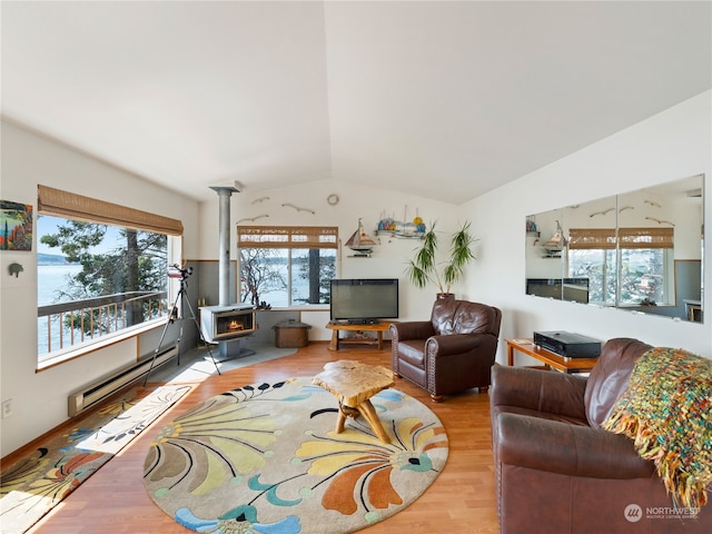 living room featuring a wood stove, light hardwood / wood-style flooring, vaulted ceiling, and baseboard heating