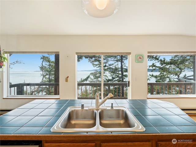 kitchen featuring sink, tile counters, a water view, and a baseboard radiator