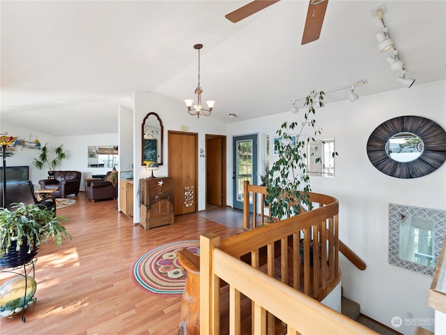 interior space with vaulted ceiling, ceiling fan with notable chandelier, hardwood / wood-style floors, and rail lighting