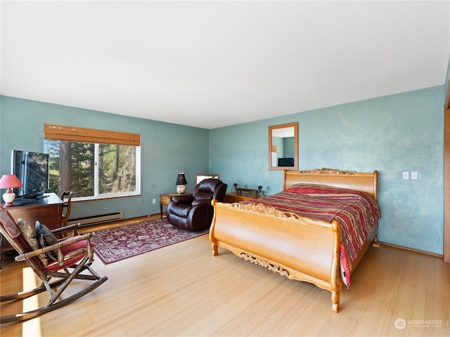 bedroom with a baseboard heating unit and light hardwood / wood-style flooring